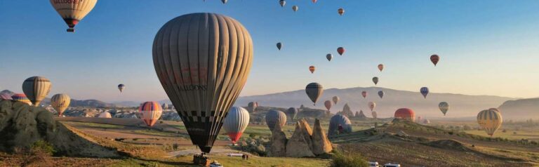 Colorful hot air balloons floating over the unique rock formations and fairy chimneys of Cappadocia, Turkey at sunrise